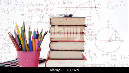Stack of six hardcover books leaning on desk in studio, with colored pencils and watercolor palette Stock Photo