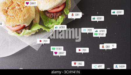 Showing two sesame burgers resting on paper at table, with floating notification icons, copy space Stock Photo