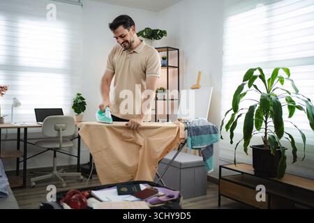 Man ironing clothes before business trip in hotel room Stock Photo