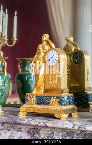 Close-up on golden clock, green porcelain vase and candlestick reflected on mirror of vintage house Stock Photo