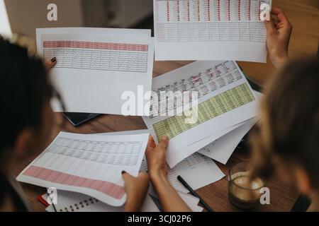 Hands holding printed data charts during collaborative analysis session Stock Photo