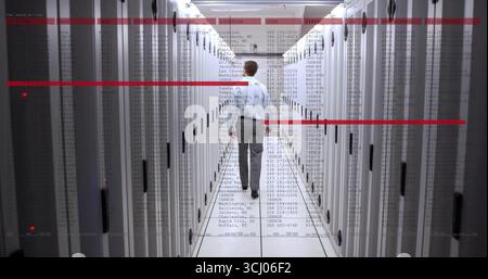 Walking technician in blue shirt gray pants passing through data center with racks, digital overlay Stock Photo