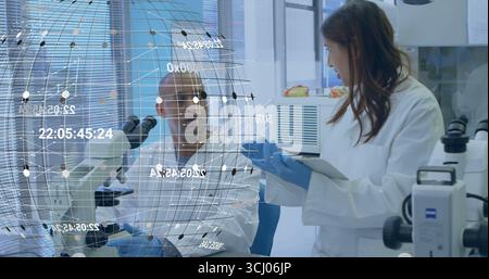 Discussing hologram data two scientists wearing white lab coats at lab bench, using tablet computer Stock Photo