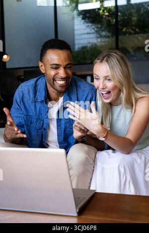 Celebrating engagement, diverse couple video chatting on laptop at home Stock Photo