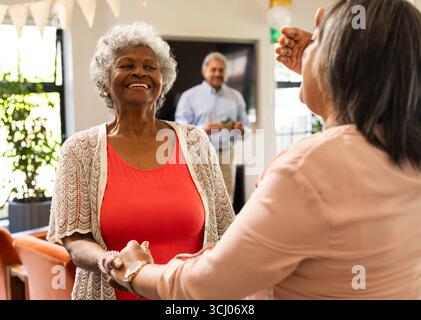 Senior diverse senior women dancing joyfully at home during celebration Stock Photo
