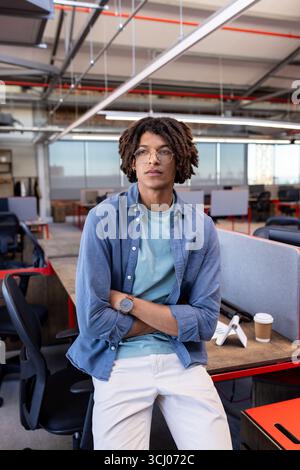 Confident man in modern office wearing casual attire, standing with arms crossed Stock Photo