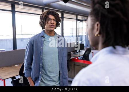Two colleagues discussing project in modern office, fostering creative collaboration Stock Photo