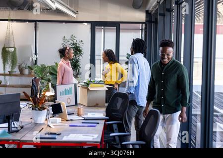 Colleagues in modern office discussing project, smiling and collaborating near desk Stock Photo