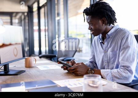 African American man using tablet and computer at office, analyzing data charts Stock Photo