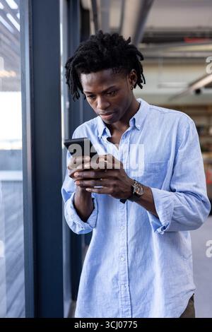 Young man in office using smartphone, concentrating on work tasks Stock Photo