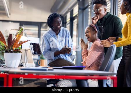 African American colleagues laughing and collaborating in modern office environment Stock Photo