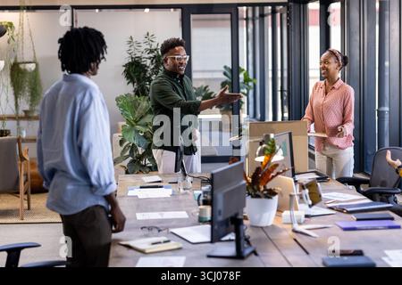 Colleagues discussing project ideas in modern office, smiling and collaborating Stock Photo