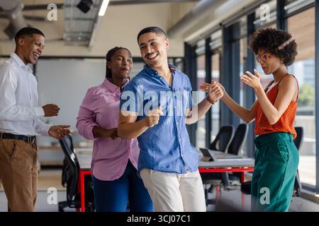 Dancing and laughing, colleagues enjoying lively break together in office Stock Photo