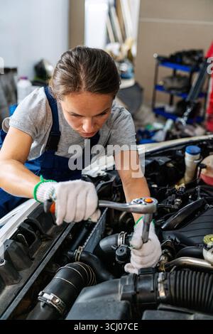 Young woman auto mechanic repairing car at repair garage. Woman at work. Stock Photo