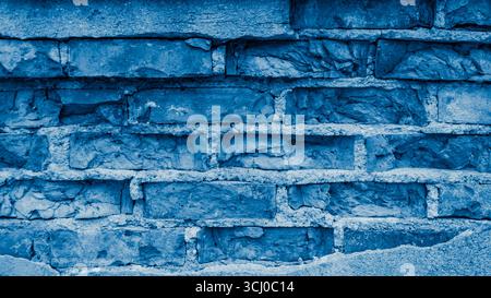 a wall made of old bricks with peeling blue plaster Stock Photo