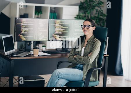 Professional software developer working remotely in her stylish home office with dual monitors showcasing programming code Stock Photo