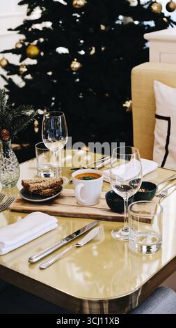Elegant restaurant table setting with a festive Christmas atmosphere. A gourmet dish of fish fillet served on a bed of vegetables and olives is plated Stock Photo