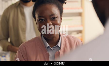 Medicine buying customers in pharmacy African woman smiling health care buying pills drugs pharmacist man help medical assisting cleint buy medication Stock Photo