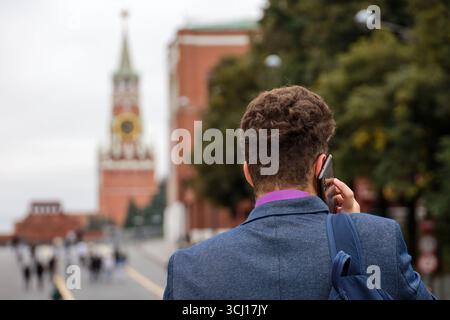 Man talking by mobile phone standing on Red square and Kremlin background Stock Photo