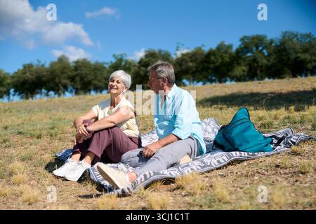 Senior couple relaxing on blanket in nature, enjoying retirement together Stock Photo