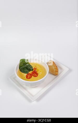 healthy pumpkin soup in a bowl with a spoon on a white plate with a pie. Stock Photo