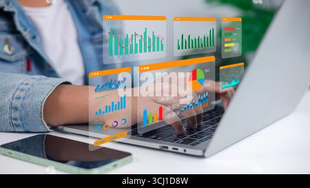 Business data analytics concept with person working on laptop computer, surrounded by 3D hologram charts and graphs. Perfect for finance, marketing, b Stock Photo