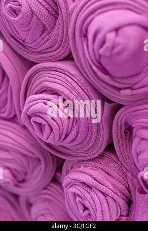 Knitted pink fabric rolled into rolls, close up shot, abstract textile background Stock Photo