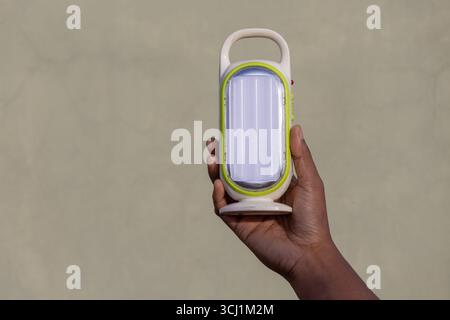 Close-up of a female hand holding a compact, rechargeable LED light. The powerful emergency light doubles as a portable power bank, making it ideal fo Stock Photo