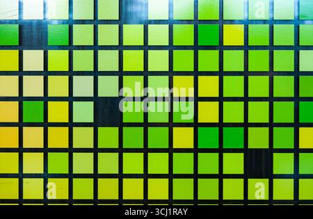 Mosaic of small green-yellow squares on glass, close-up. Matrix style digital squares. Stock Photo