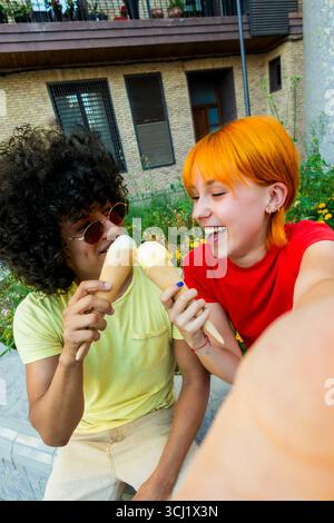 Happy multi-ethnic couple taking a selfie while eating ice cream outdoors Stock Photo