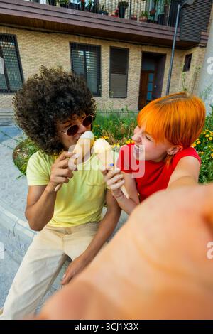 Happy couple taking a selfie while eating ice cream outdoors Stock Photo