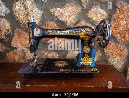 Setenil de las Bodegas, Spain - March 11, 2025: Antique black sewing machine with gold detail placed on wood surface. Rustic decor at local restaurant Stock Photo