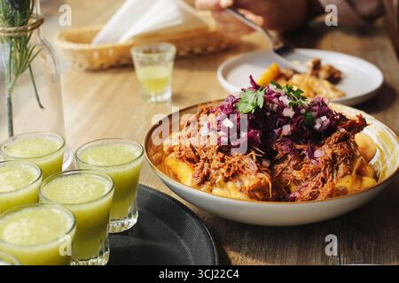 Pulled pork with fries. Tasty meat dish on table. Fresh food with red cabbage. Traditional comfort meal with drinks. Restaurant dining background. Stock Photo