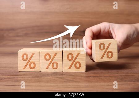 Man putting wooden cube with percent sign next to others on table, closeup Stock Photo