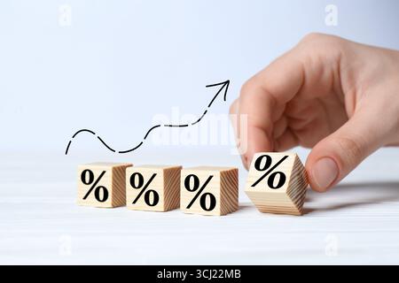 Man holding wooden cube with percent sign at white table, closeup Stock Photo