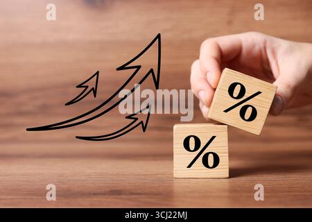 Man holding wooden cube with percent sign at table, closeup Stock Photo