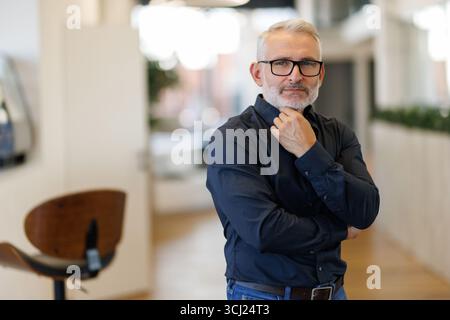 Serious mature 45 years old business man investor standing in office looking away. Stock Photo