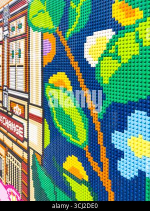 Colorful Lego mosaic wall art depicting a vibrant floral and building design with intricate details and vivid colors Stock Photo
