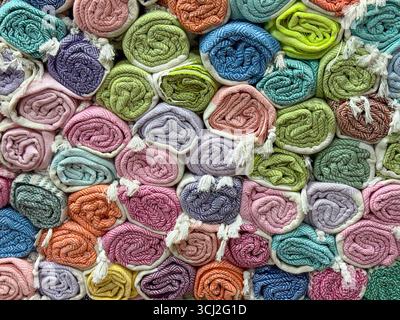 Rolled textiles with herringbone patterns in red, orange and gray stacked in a shop. Design, comfort and consumer choice represented through woven Stock Photo