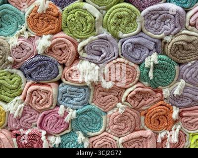 Rolled textiles with herringbone patterns in red, orange and gray stacked in a shop. Design, comfort and consumer choice represented through woven Stock Photo