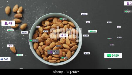 Displaying ceramic bowl holding shelled almonds on gray tabletop showing floating reaction icons. Snack, charisma, minimalist, digital, engagement, or Stock Photo