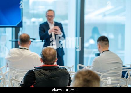 Business professional giving presentation to engaged audience in modern conference setting with natural light Stock Photo