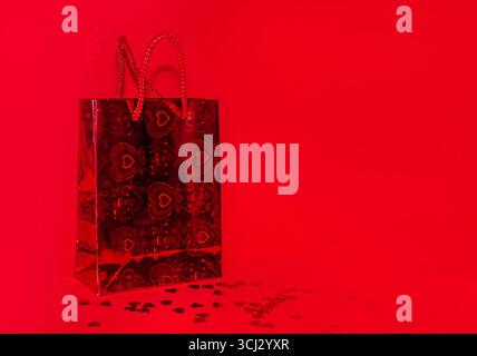 Red shopping bag on red background with red confetti and copy space. Stock Photo