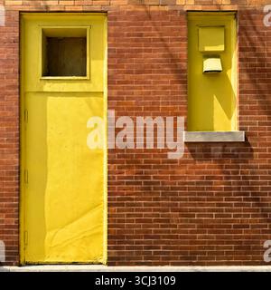 Industrial yellow painted warehouse door in plain red brick wall of Chicago building. Stock Photo