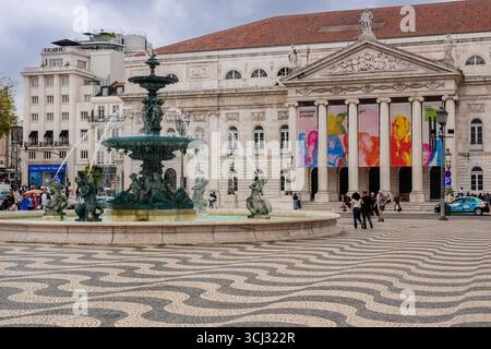 The North Fountain surrounded by the wavy tile patterned pavement by the National Theatre at Rossio Square in Lisbon, Portugal. The central square honors King Peter IV of Portugal. Stock Photo