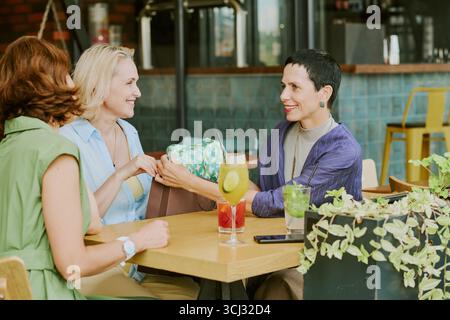 Three Middle Aged Women Socializing and Smiling at Outdoor Cafe Stock Photo