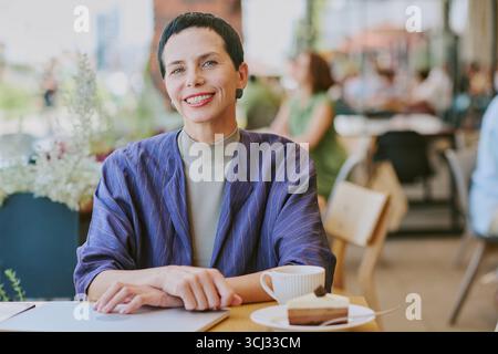 Portrait of Middle Aged Woman Smiling While Sitting at Cafe Table Stock Photo