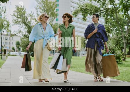 Three Middle Aged Women Strolling Outdoors Carrying Shopping Bags Stock Photo