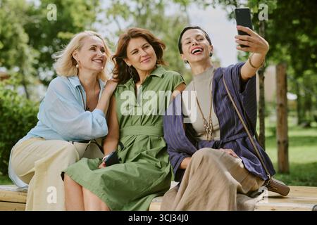Three Middle Aged Women Smiling While Taking Selfie Outdoors Stock Photo