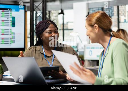 Multiethnic team of managers strategizing in a meeting with data reports, analyzing finance information on papers to meet objectives for company synergy. Shared insight and leadership. Stock Photo